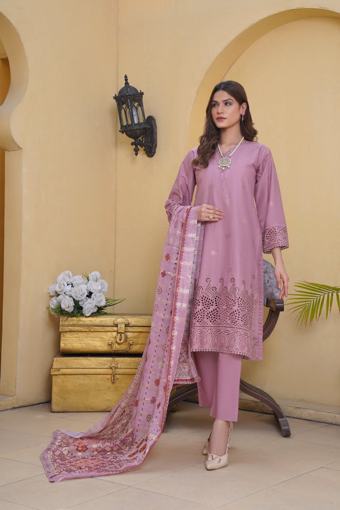 Woman posing in a stylish lavender salwar kameez with intricate patterns, indoor setting.